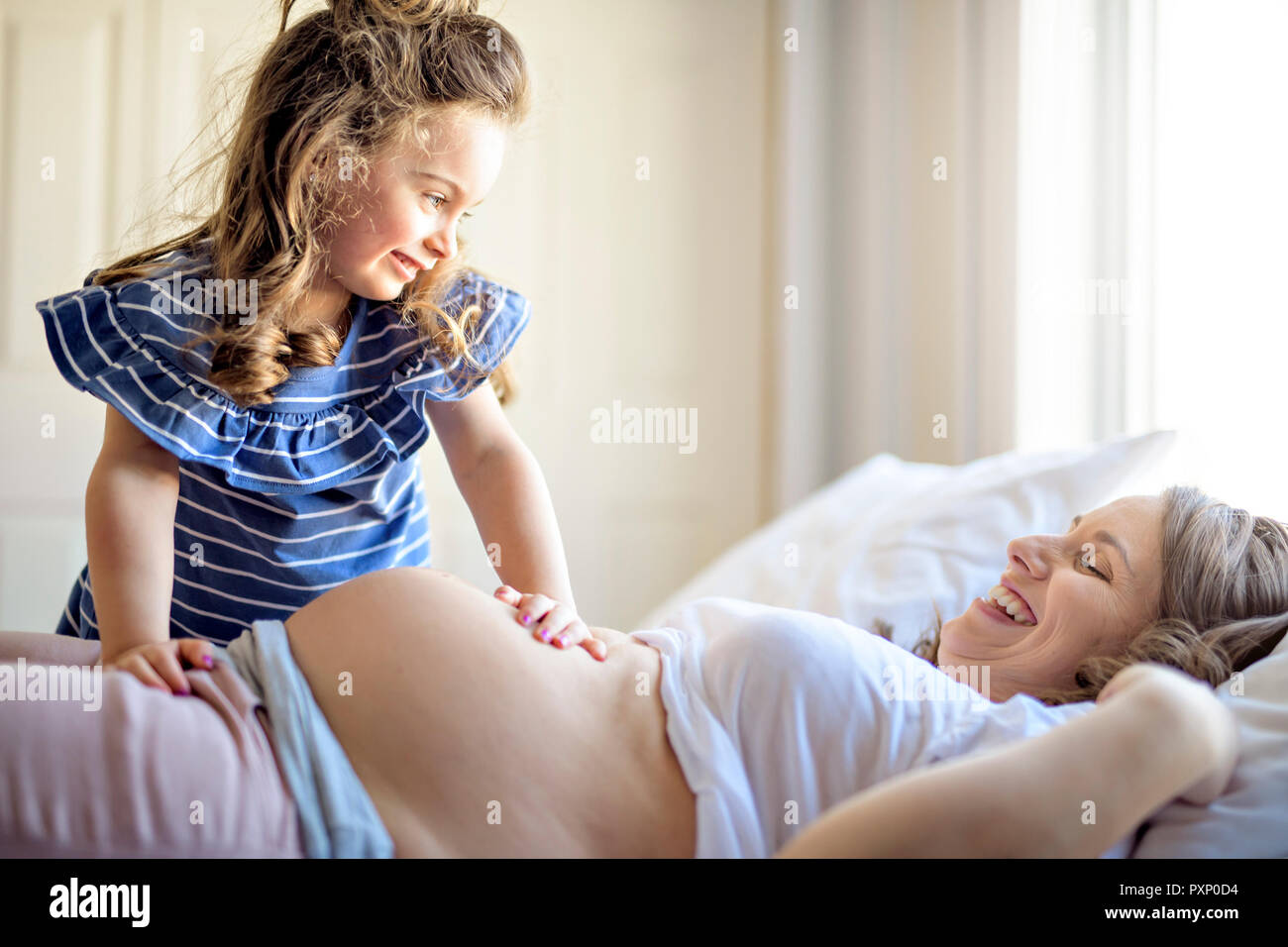 Femme enceinte avec sa fille sur l'ensemble de chambre à coucher Banque D'Images