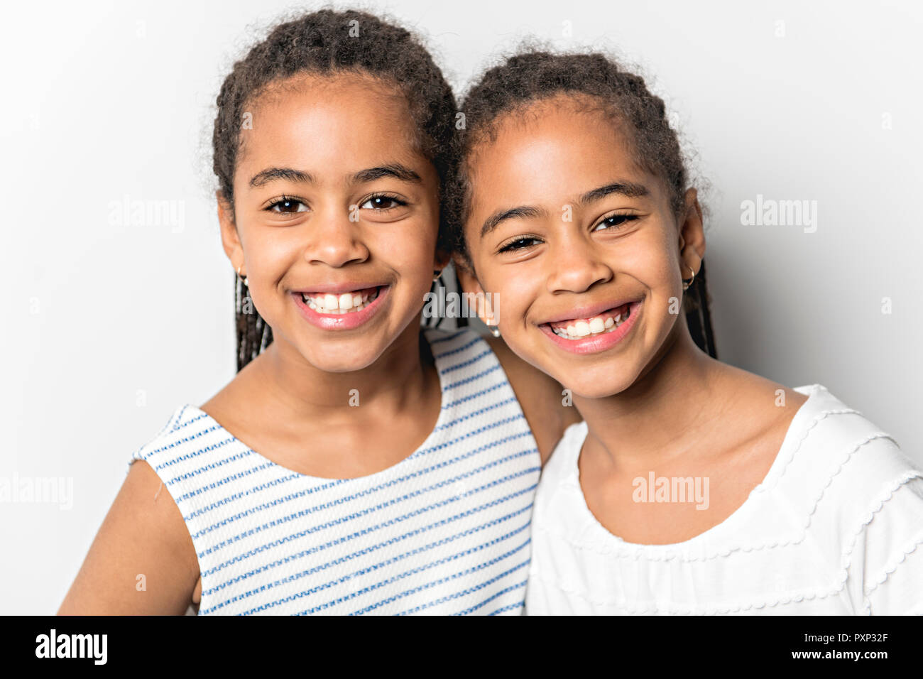 L'Afrique de l'Adorable petit studio lits jumeaux filles sur fond gris Banque D'Images