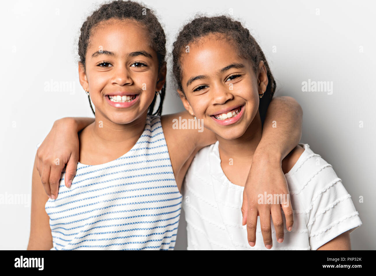L'Afrique de l'Adorable petit studio lits jumeaux filles sur fond gris Banque D'Images
