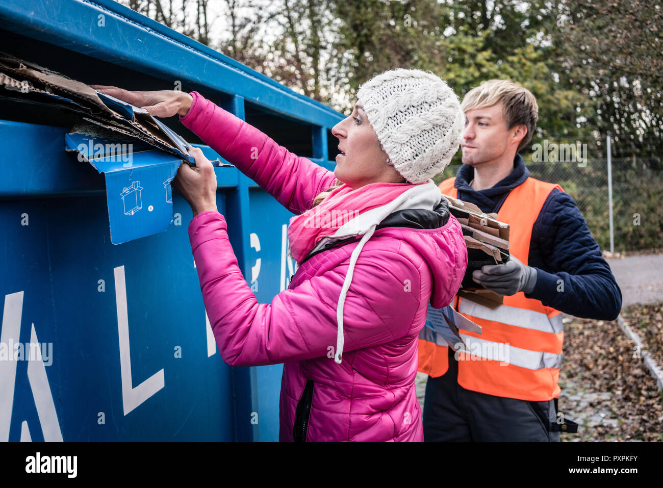 La femme et l'homme de mettre les déchets de papier dans le récipient sur le centre de recyclage Banque D'Images