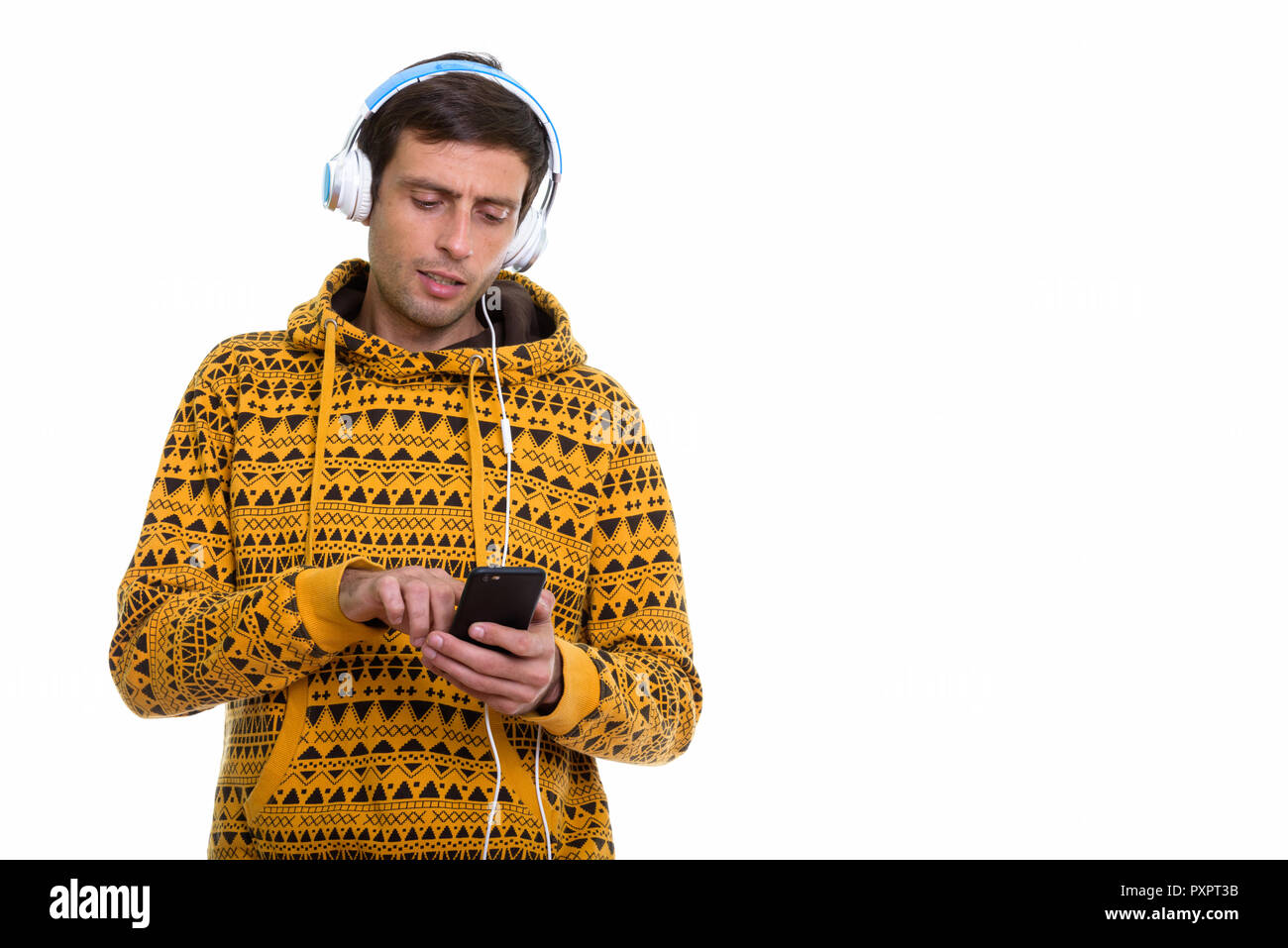 Studio shot of young man using mobile phone while liste Banque D'Images