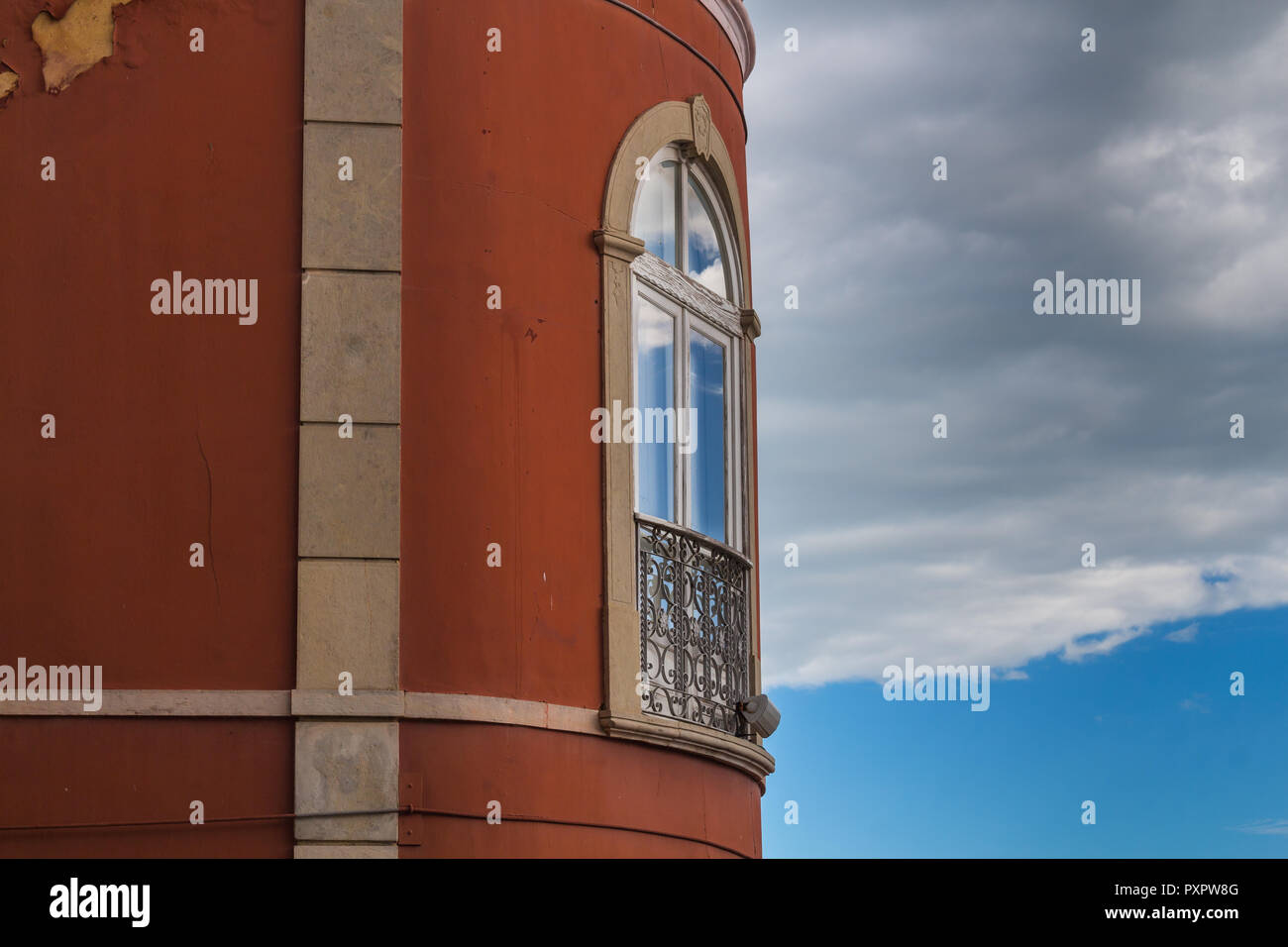 Forme arrondie de la chambre avec bourgogne façade peinte. Fenêtre avec un arc et ornementé de grille le balcon. Réflexion du ciel. Banque D'Images