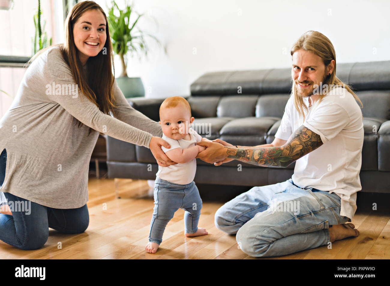 Bébé fille assistance parents prendre Premiers pas à la maison Banque D'Images