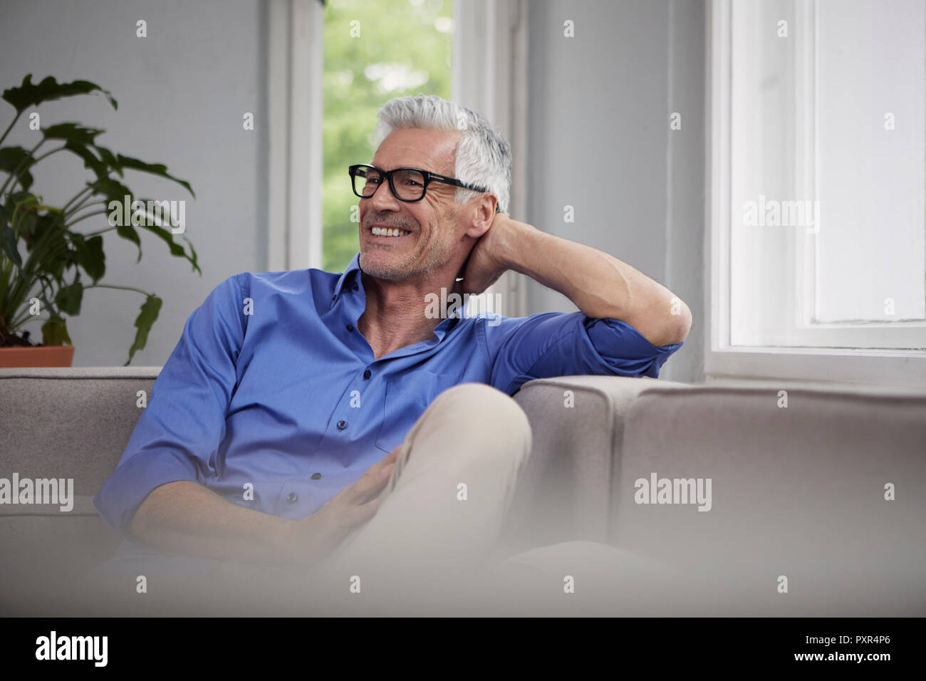 Portrait of laughing man sitting on sofa at home Banque D'Images