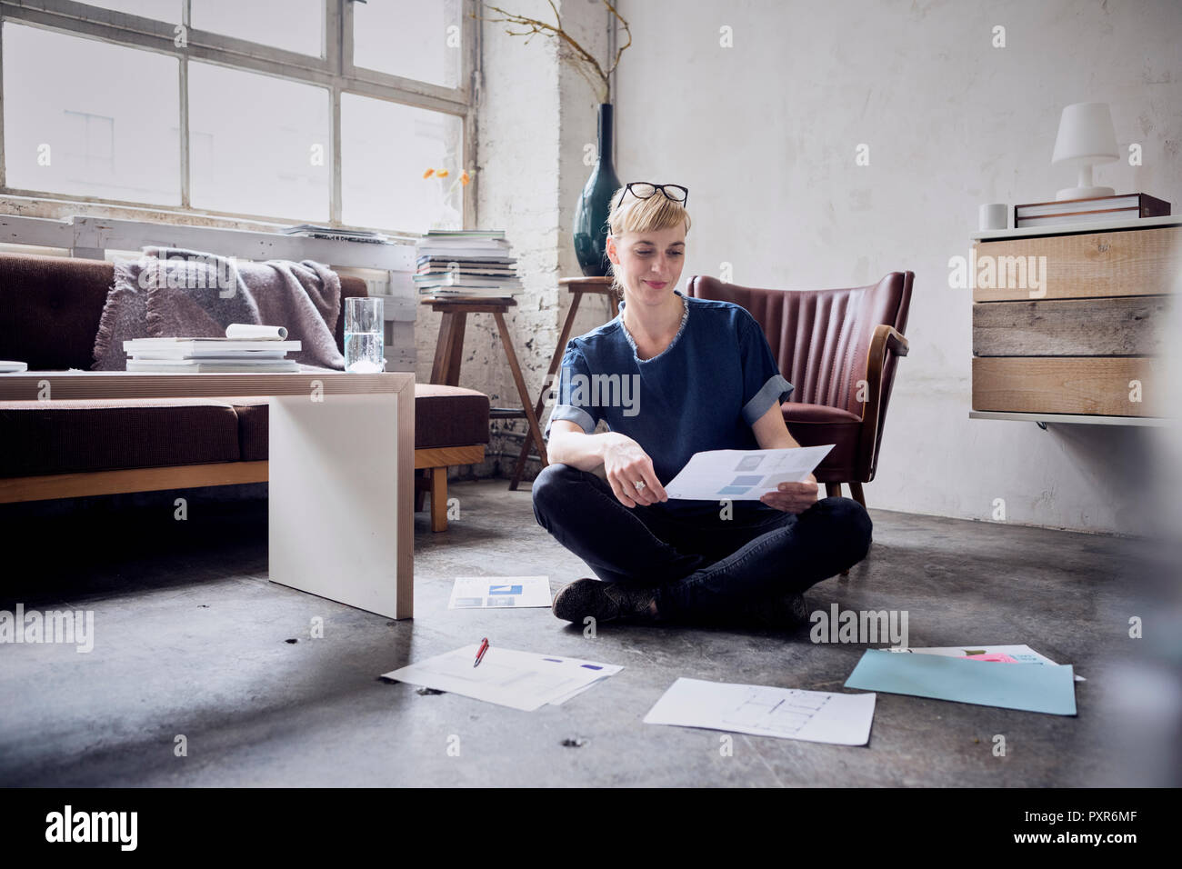 Femme assise sur le sol dans un loft de regarder des papiers Banque D'Images