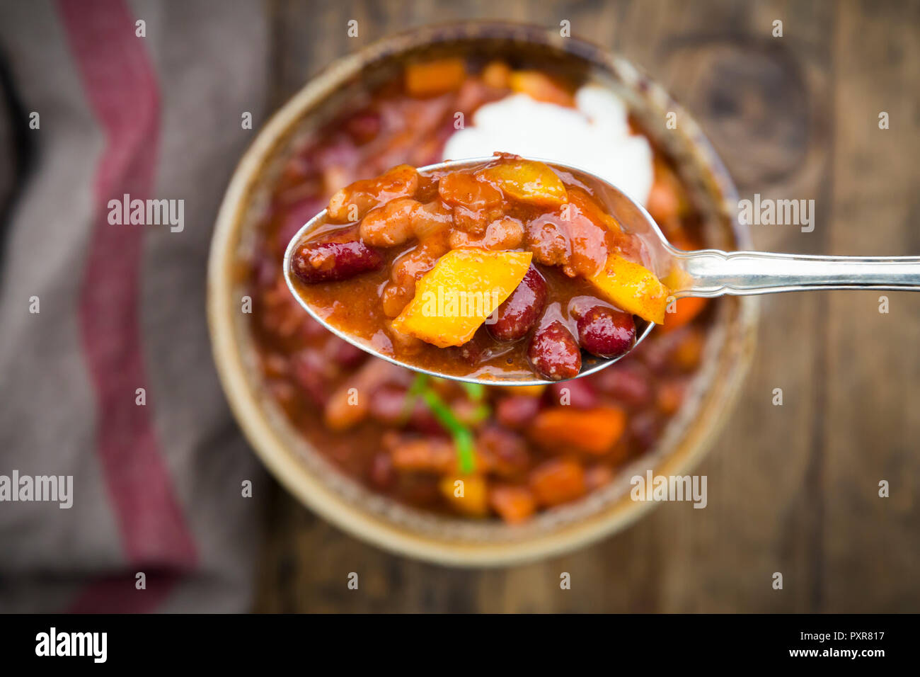 Chili con Carne avec la coriandre et la crème sure, cuillère, close-up Banque D'Images