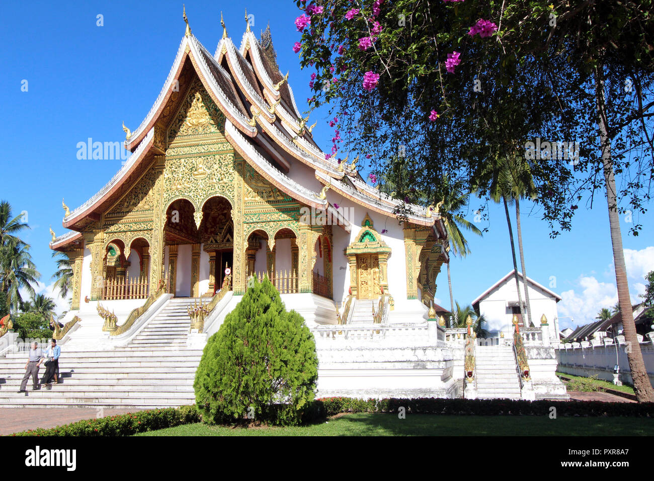 Deux visiteurs quittent la Ho Pha Bang temple au palais royal de Luang Prabang, Laos Banque D'Images