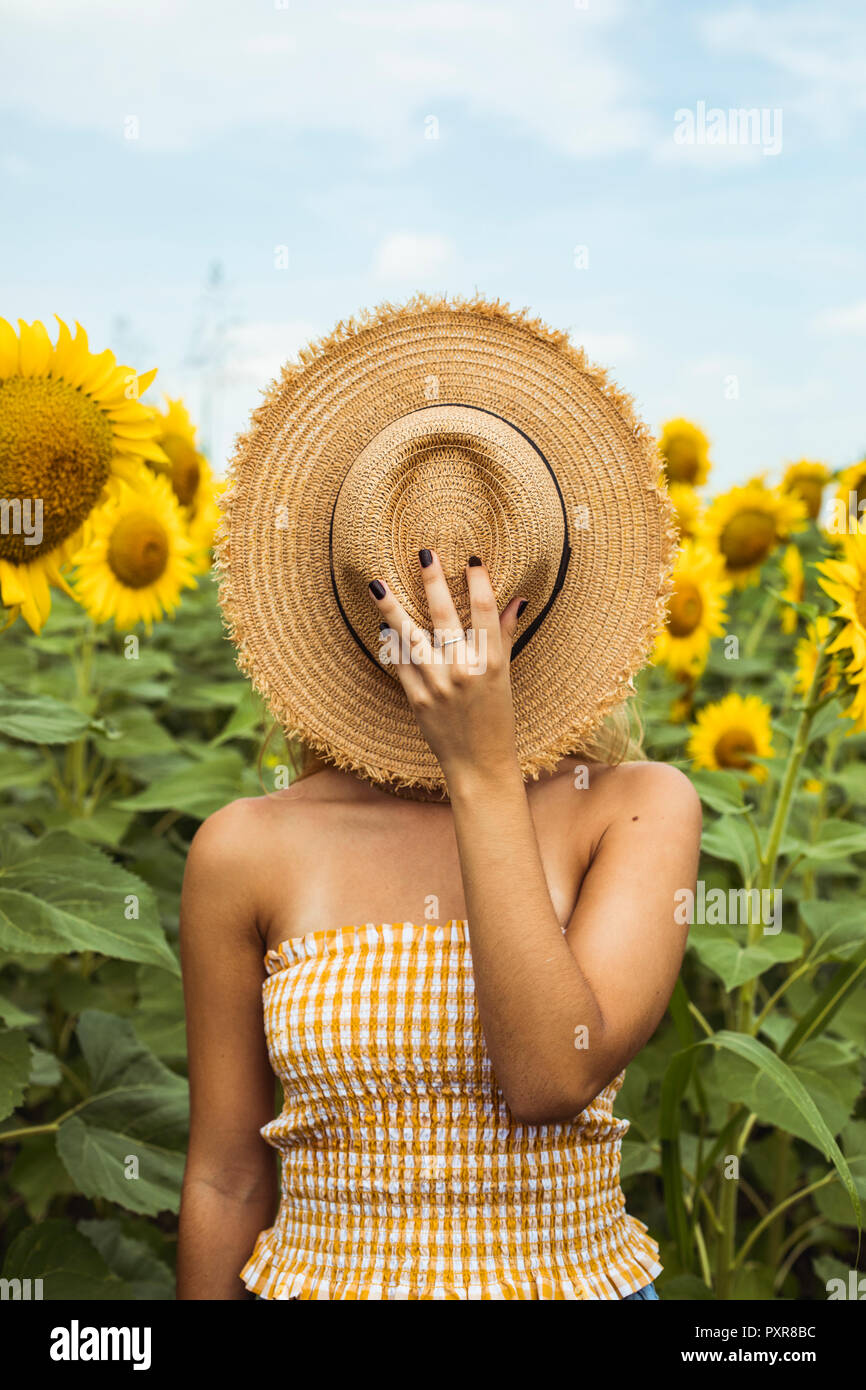 Unricognizable femme tenant un chapeau de paille dans son visage Banque D'Images