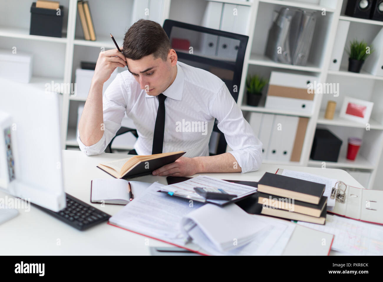 Un jeune homme qui travaille à une table dans le bureau avec un livre