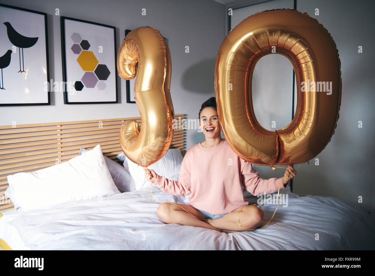 Jeune femme heureuse avec des ballons d'or, célébrant son anniversaire Banque D'Images