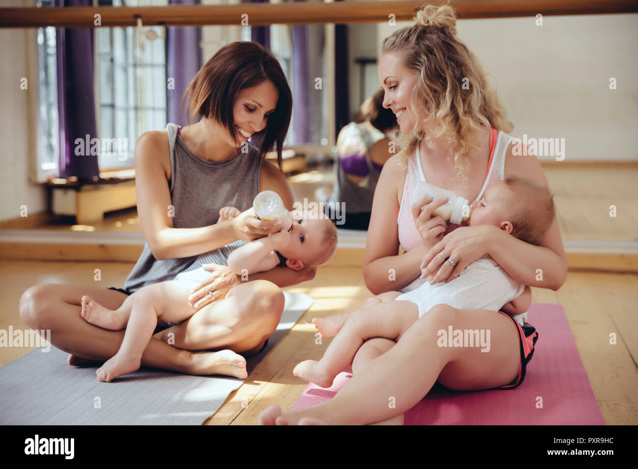 Deux mères leurs bébés au biberon dans une salle d'exercice Banque D'Images
