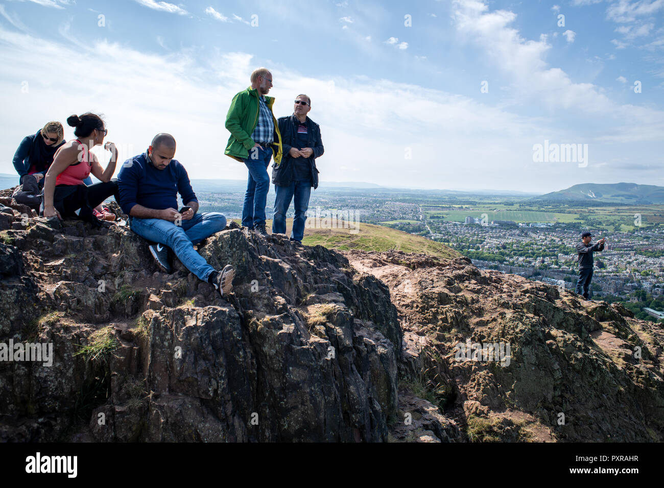 Un groupe de randonneurs s'asseoir dessus de Arthurs Seat (Holyrood Park) sur la ville scape en Ecosse Banque D'Images