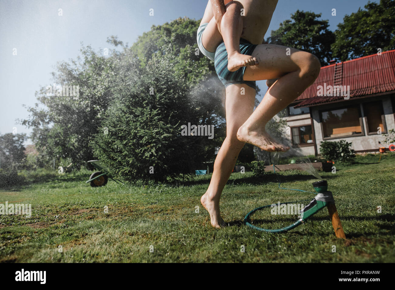 Frère et sœur jouant avec tuyau de jardin en jardin Banque D'Images