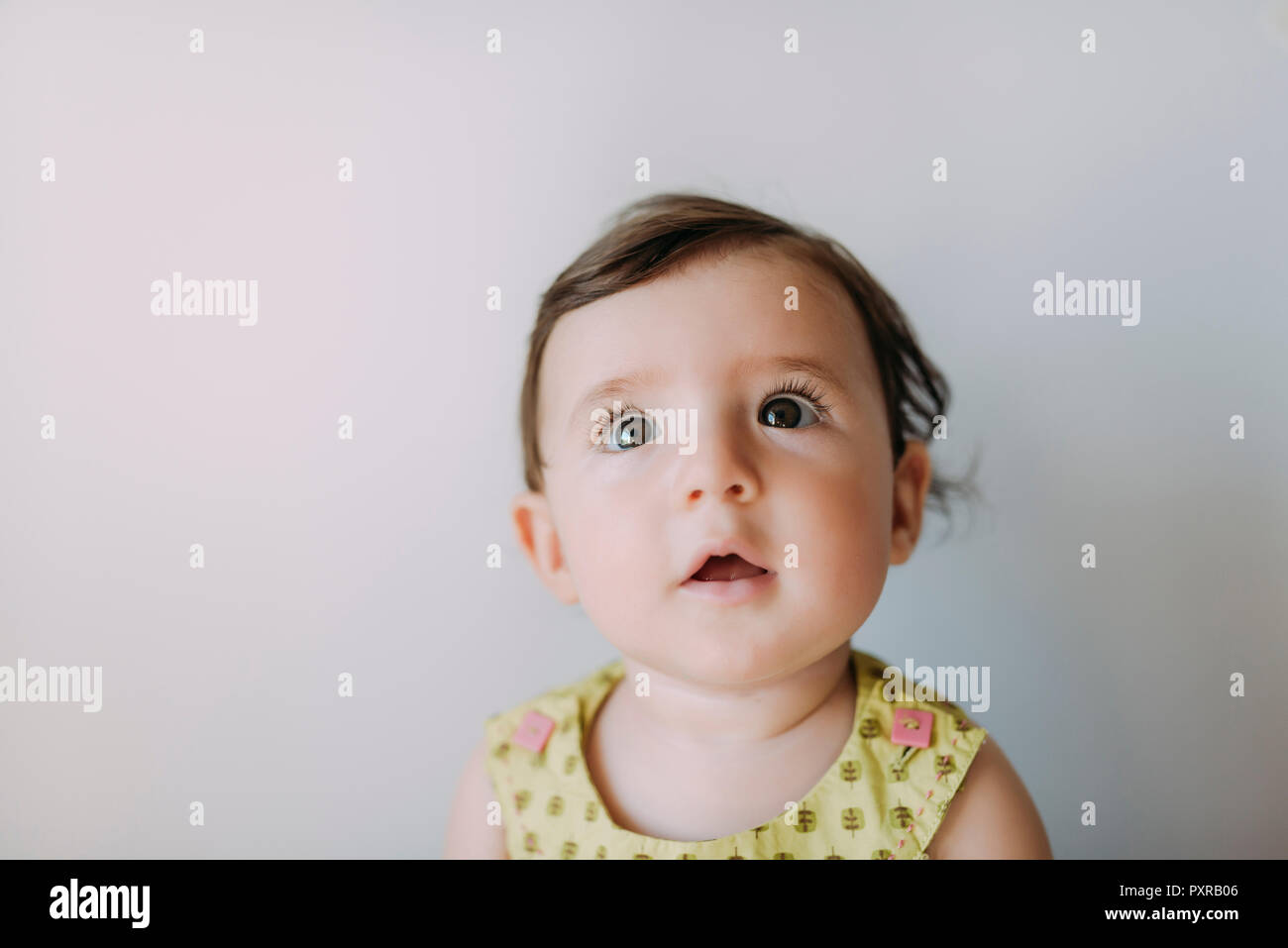 Surpris baby girl looking up on white background Banque D'Images