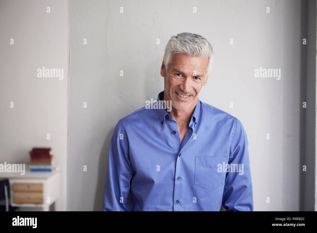 Portrait of smiling young man leaning against wall Banque D'Images