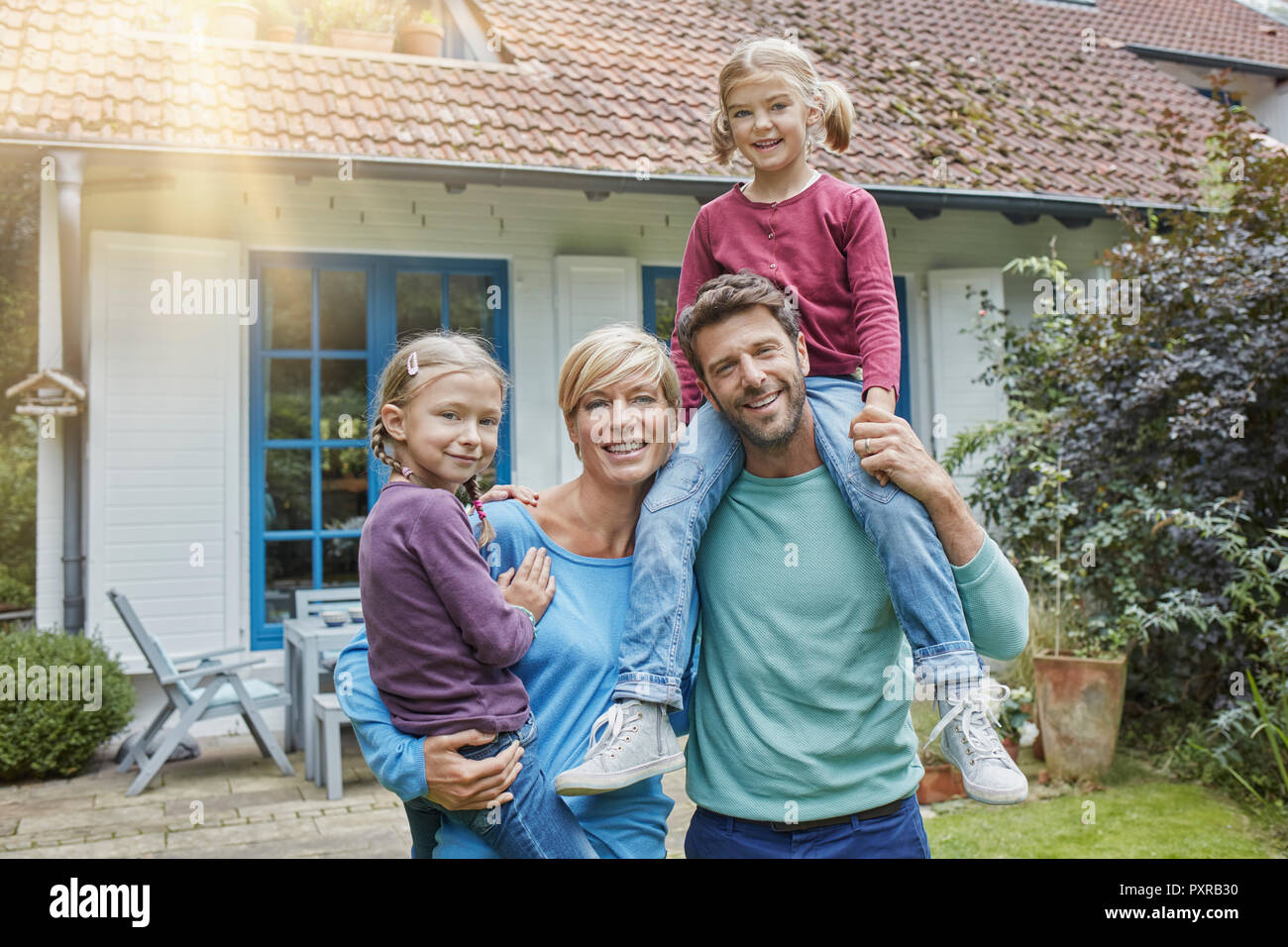 Portrait de famille heureuse avec deux enfants devant leur maison Banque D'Images