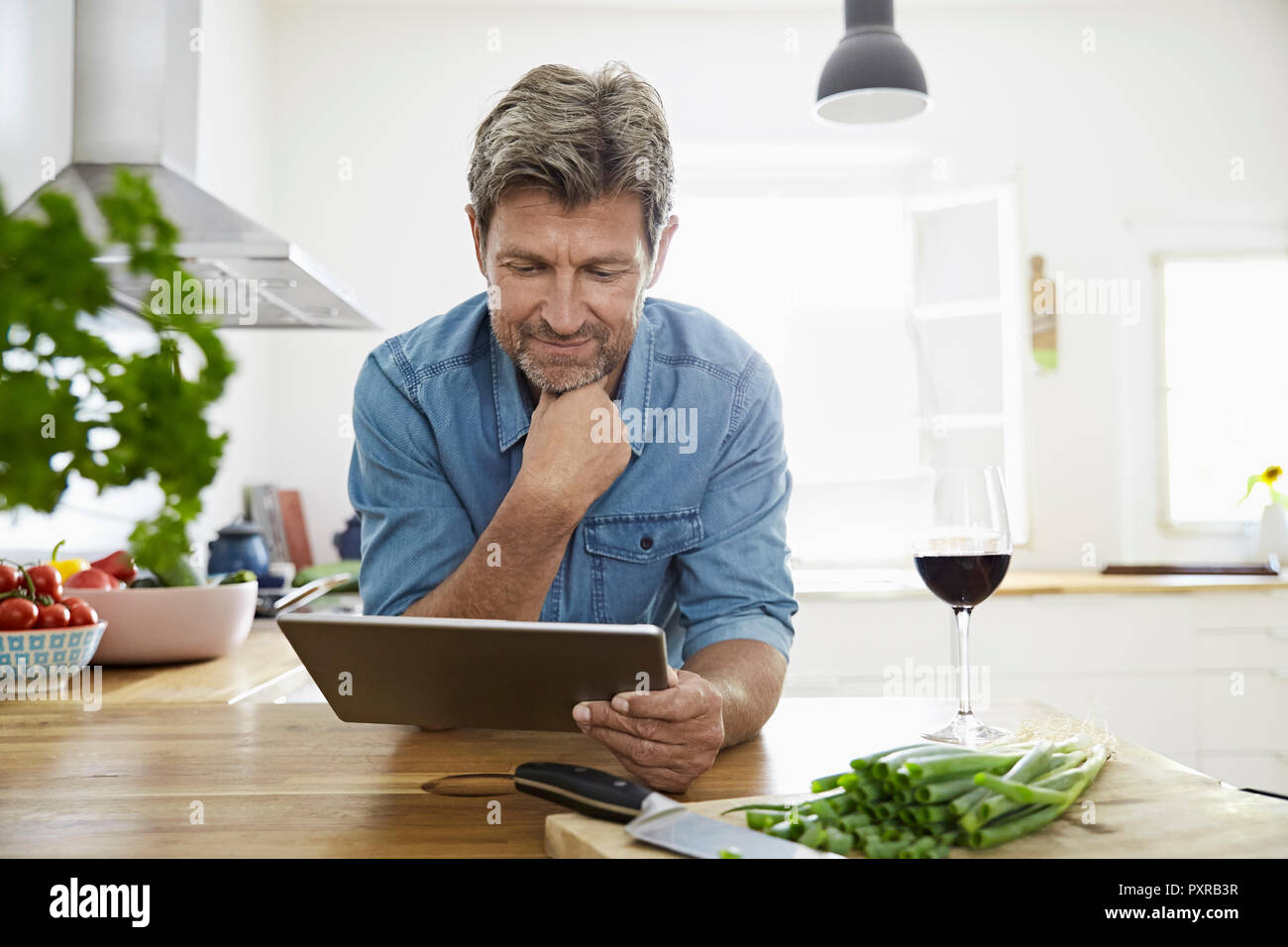 Homme mûr dans sa lecture cuisine recette sur sa tablette numérique Banque D'Images