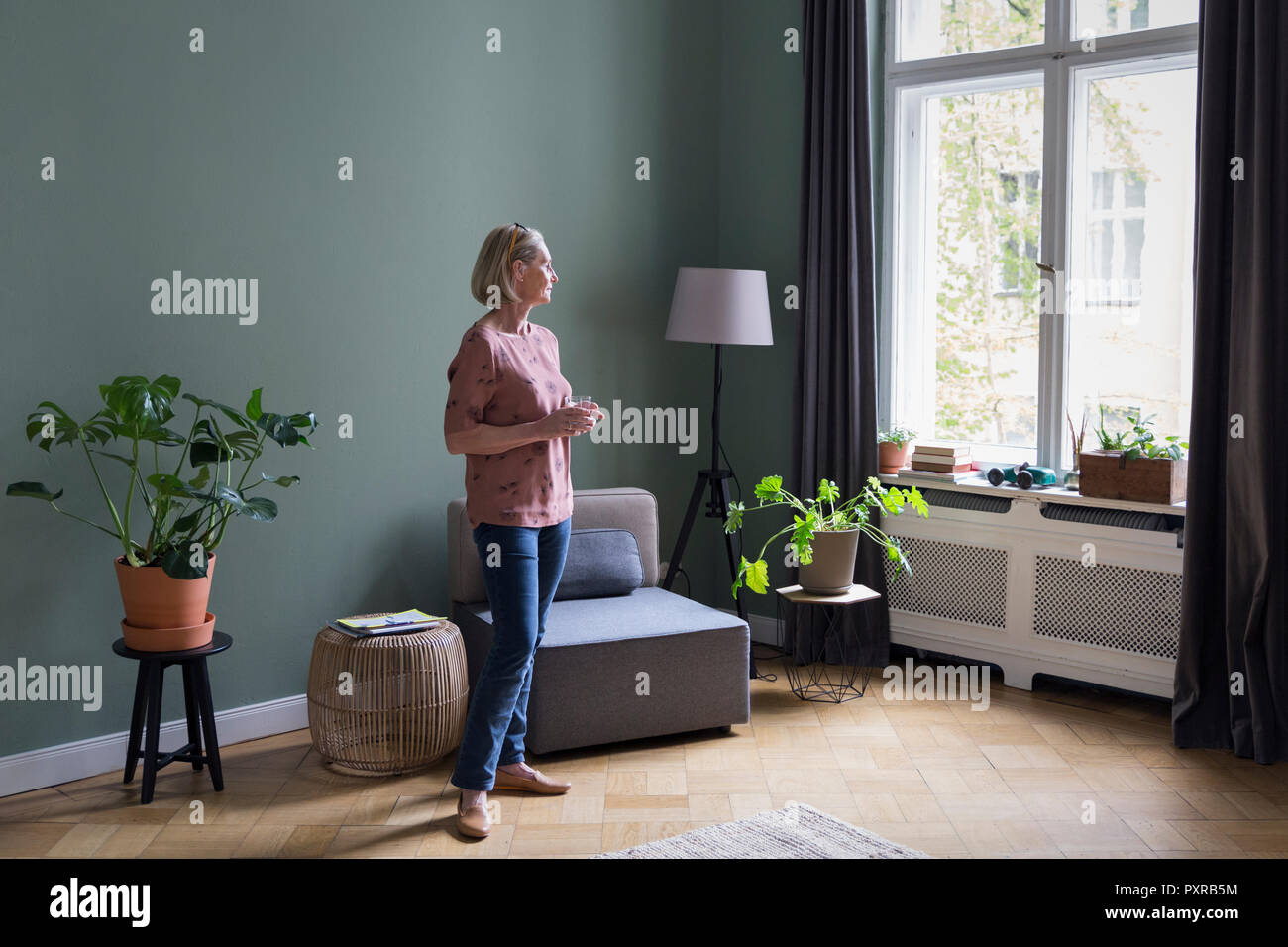 Femme mature à la maison à la fenêtre de Banque D'Images