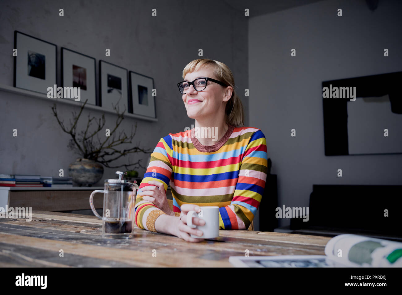 Portrait of smiling woman avec une tasse de café dans un loft Banque D'Images