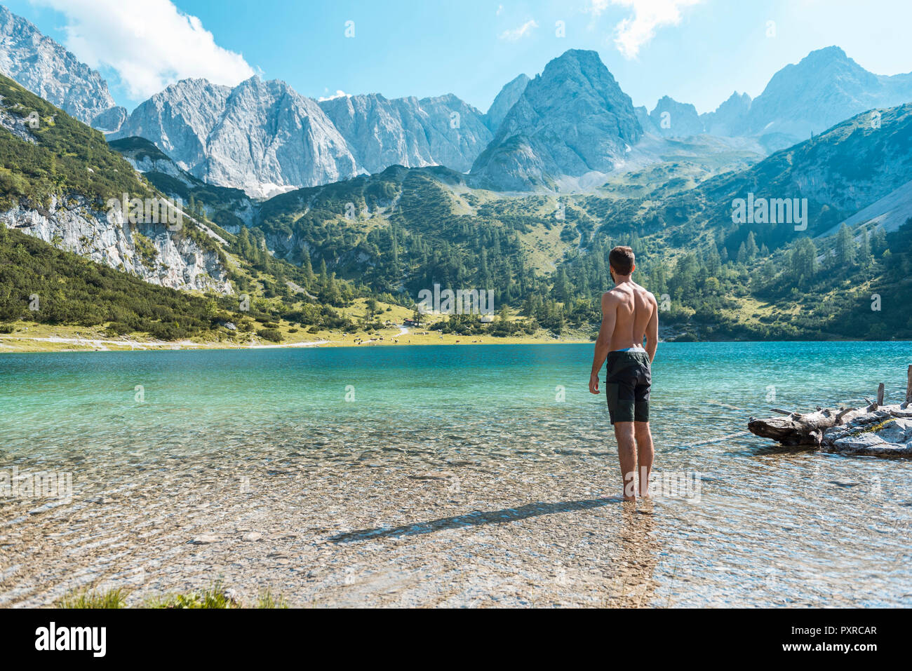 Autriche, Tyrol, jeune homme au lac Seebensee debout dans l'eau jusqu'aux chevilles Banque D'Images
