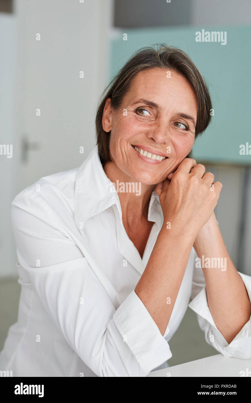 Portrait of smiling mature woman blouse blanche Banque D'Images