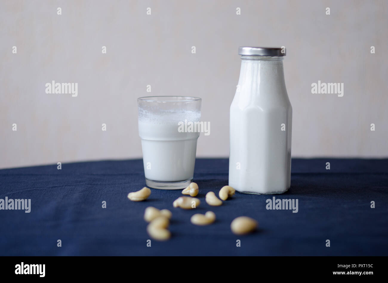 Bouteille de lait de noix de cajou et de verre se tenant ensemble avec des ingrédients à l'avant. Banque D'Images Bouteille de lait de noix de cajou et de verre se tenant ensemble avec des ingrédients à l'avant. Banque D'Images