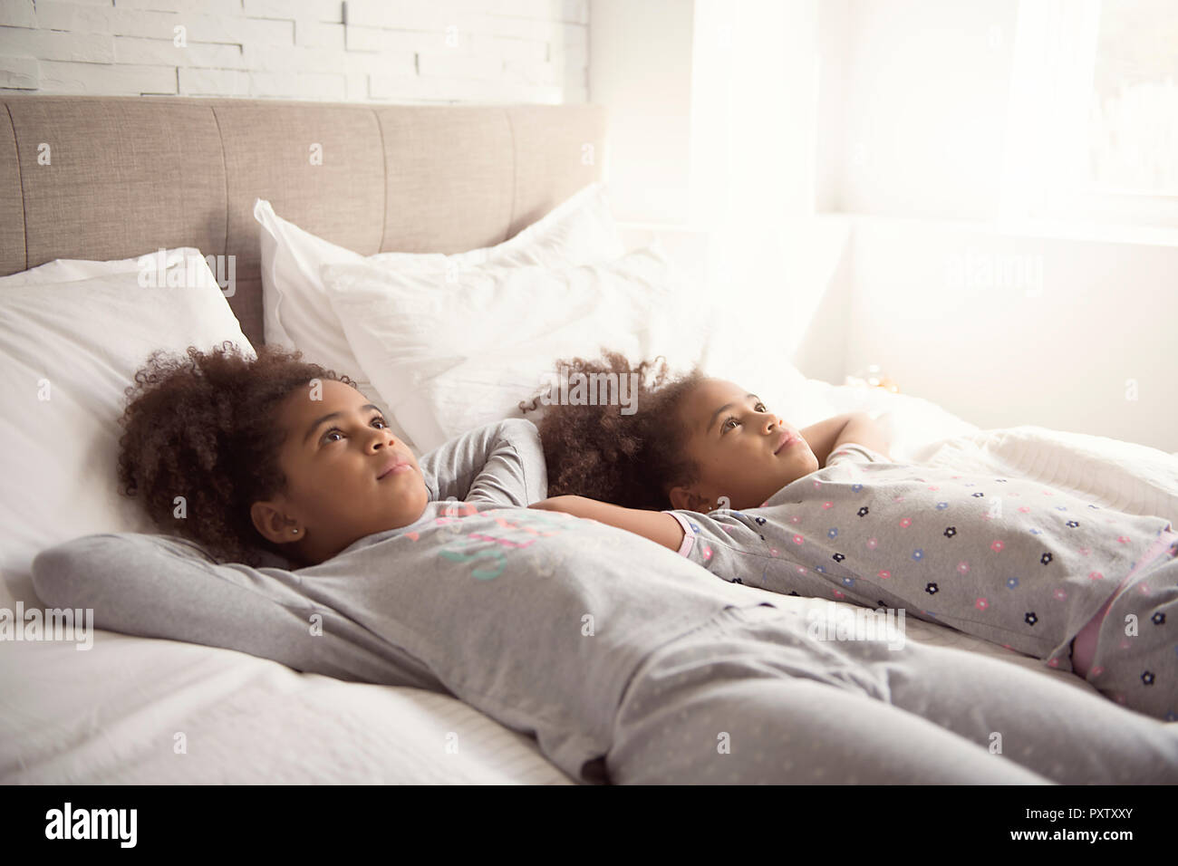 Les deux petites filles afro-américain sur le lit chez lui Banque D'Images