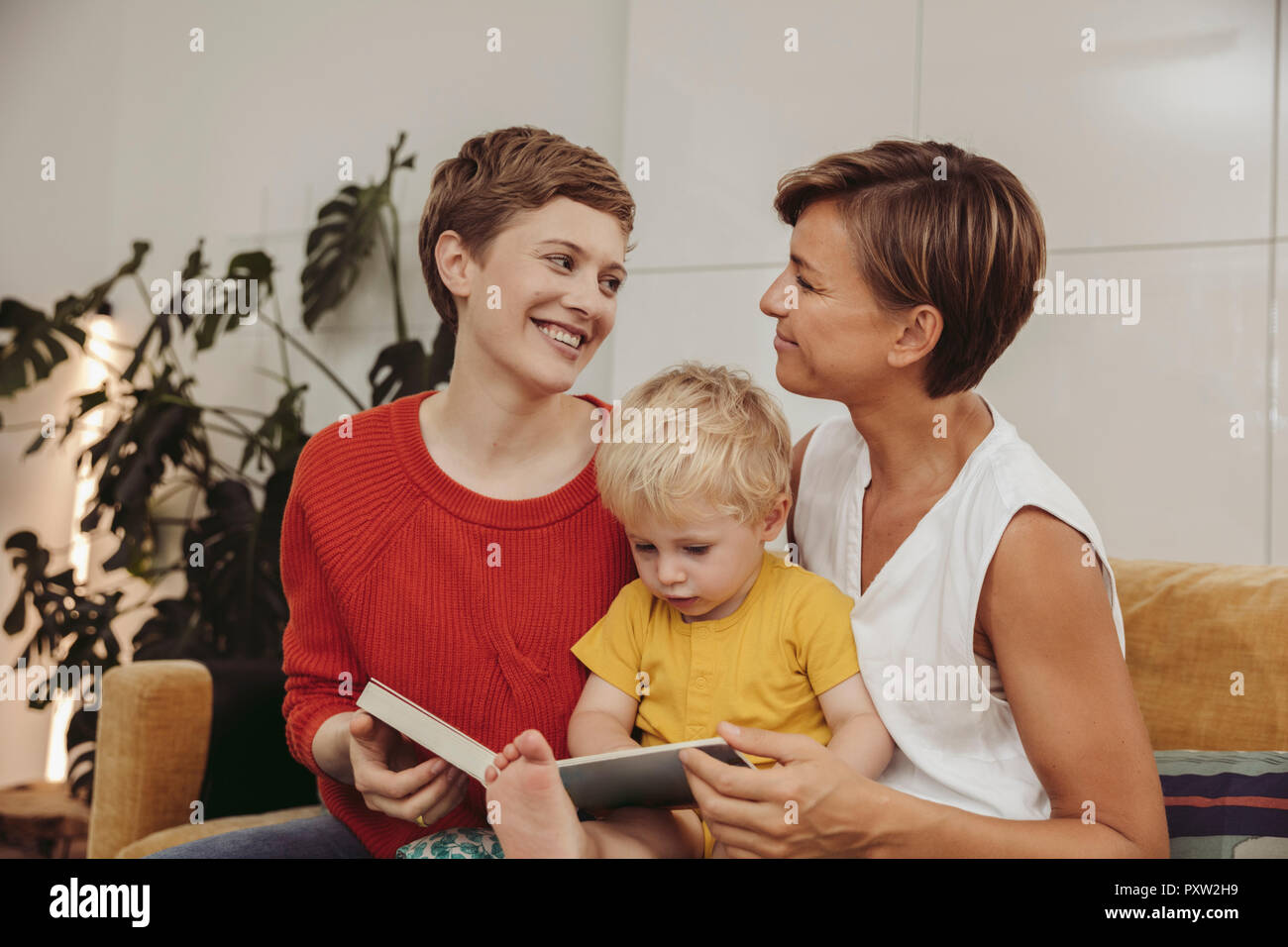 Deux mères de la lecture d'un livre avec leur enfant à la maison Banque D'Images