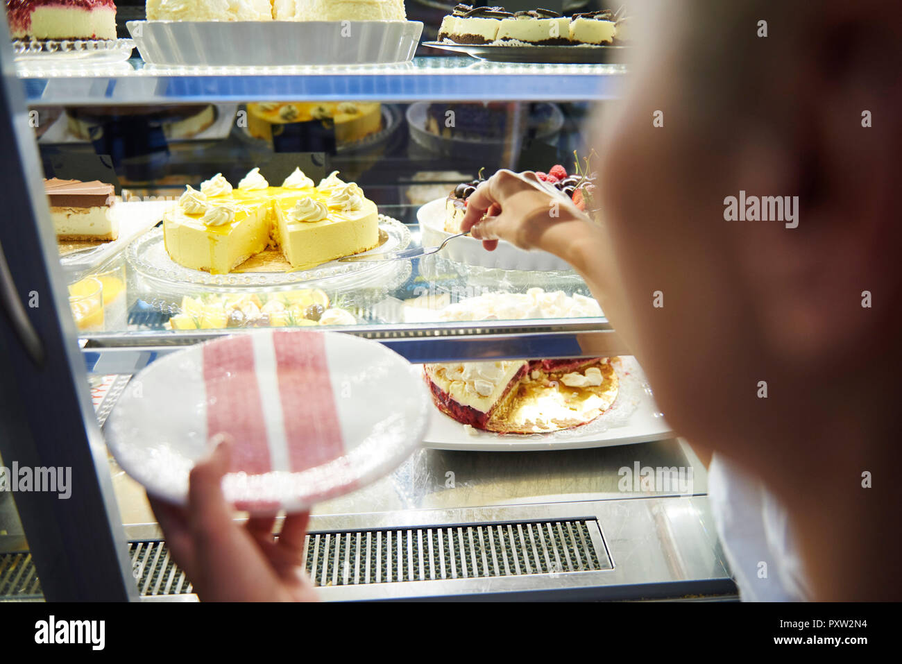 Femme travaillant dans un café proposant un morceau de gâteau Banque D'Images