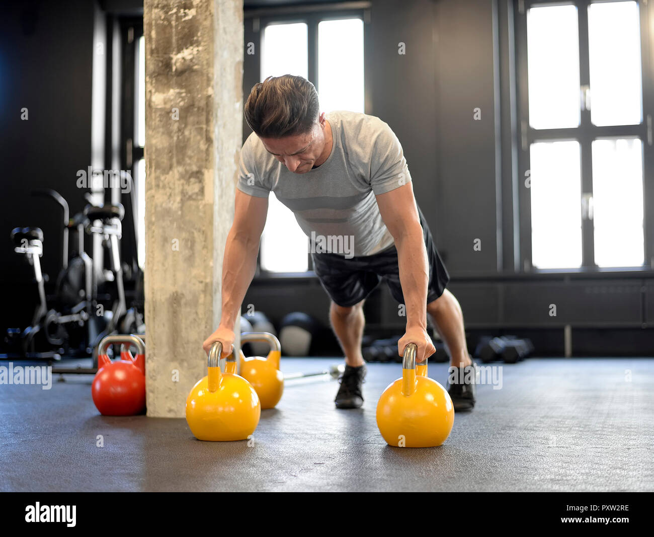 Man doing pushups sur kettlebells at gym Banque D'Images