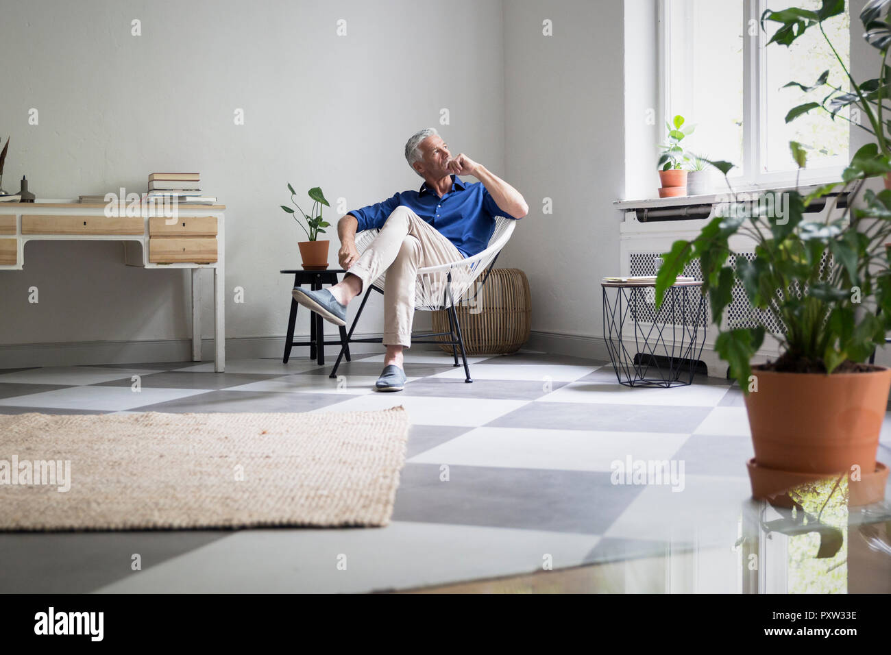 Homme mûr assis à la maison pensant Banque D'Images