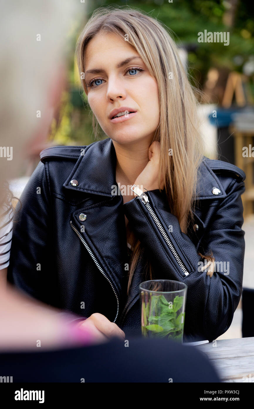 Portrait d'une jeune femme assise dans un café en plein air, à la recherche à un ami Banque D'Images Portrait d'une jeune femme assise dans un café en plein air, à la recherche à un ami Banque D'Images