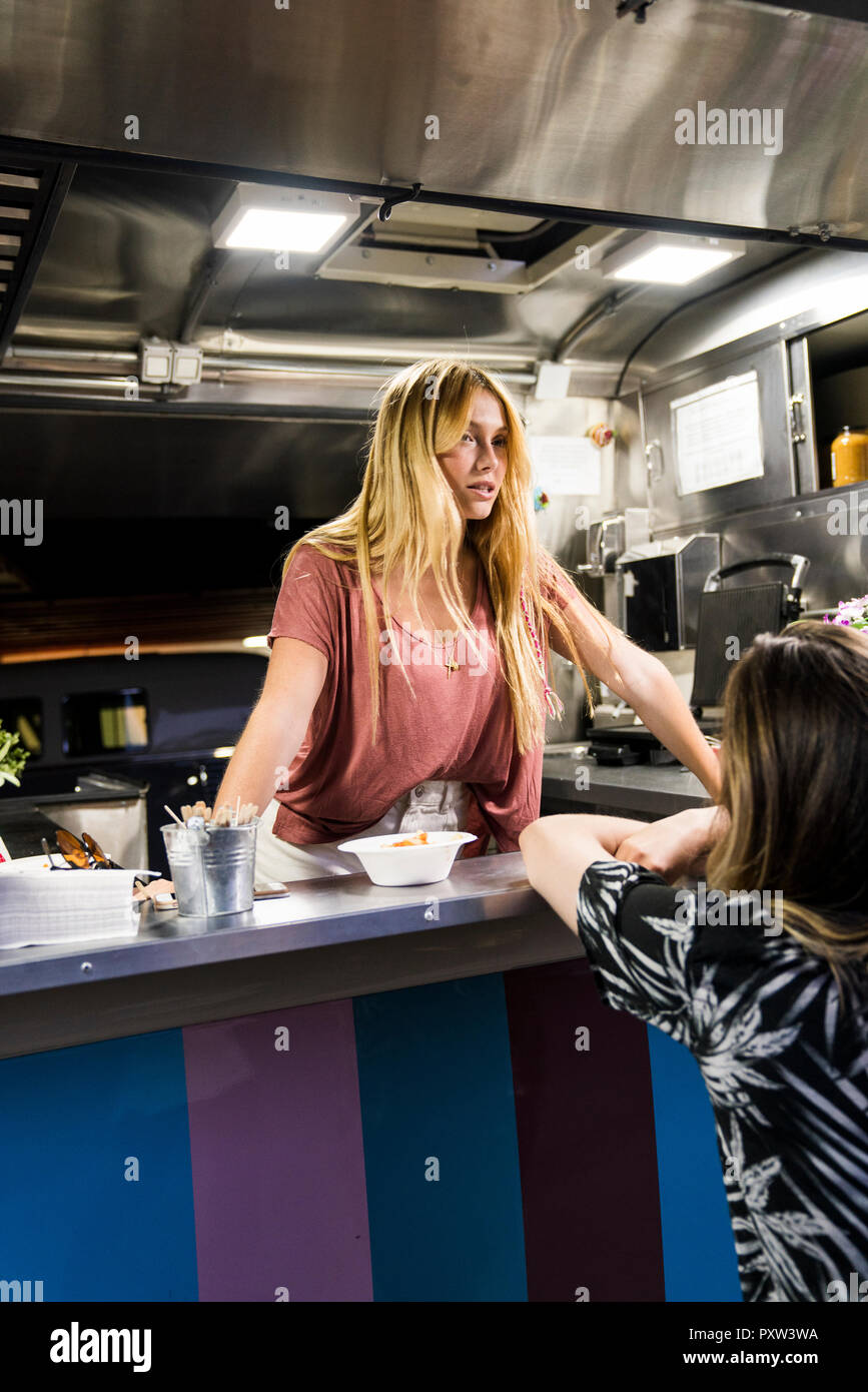 Jeune femme dans un camion alimentaire parler au client Banque D'Images