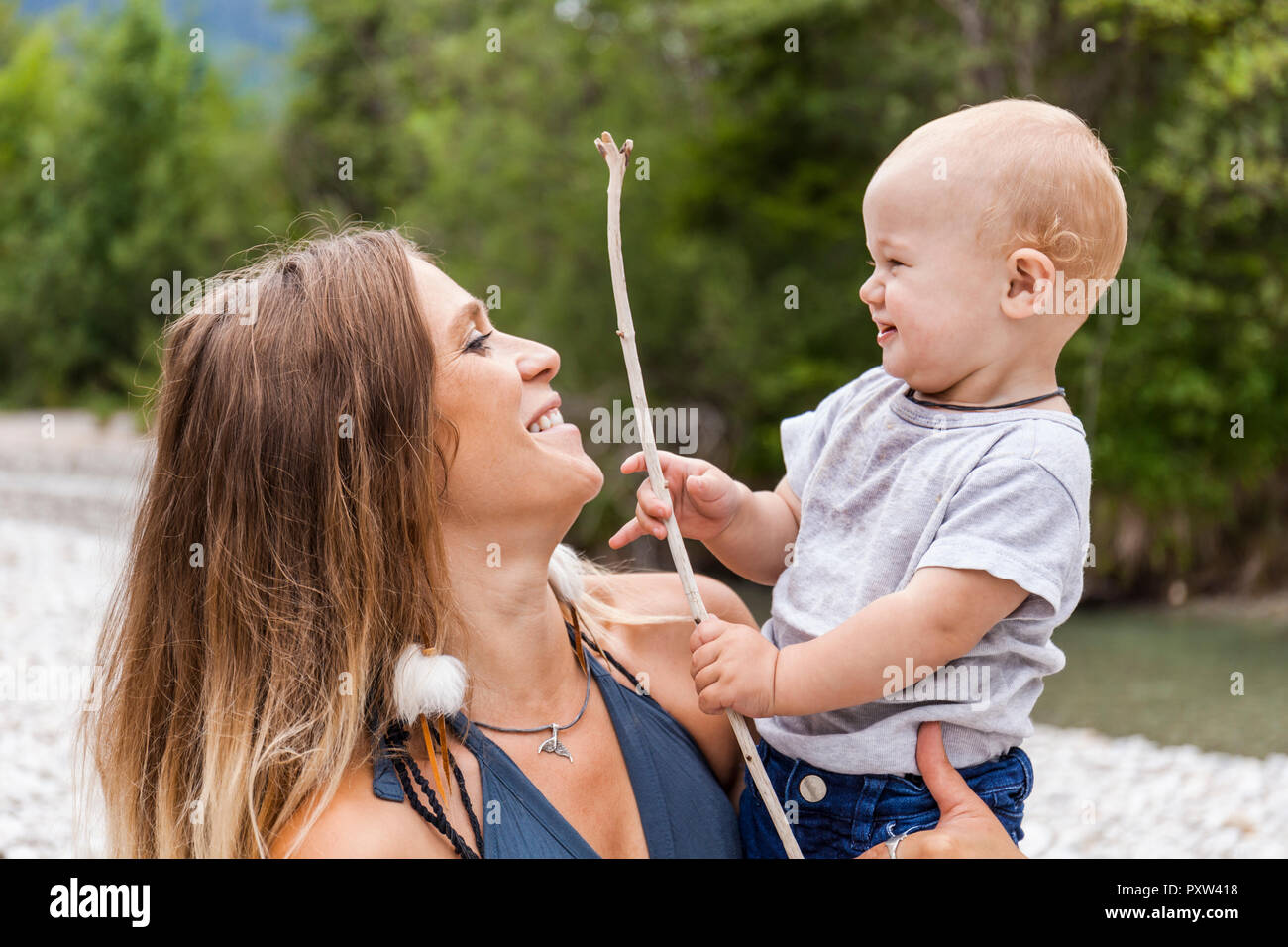 Smiling mother with baby boy holding un bâton dans la nature Banque D'Images