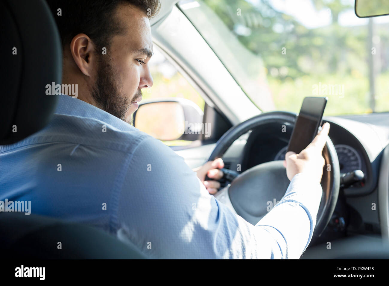 Un gros plan, portrait d'hommes occupant jusqu'cellphone on car Banque D'Images