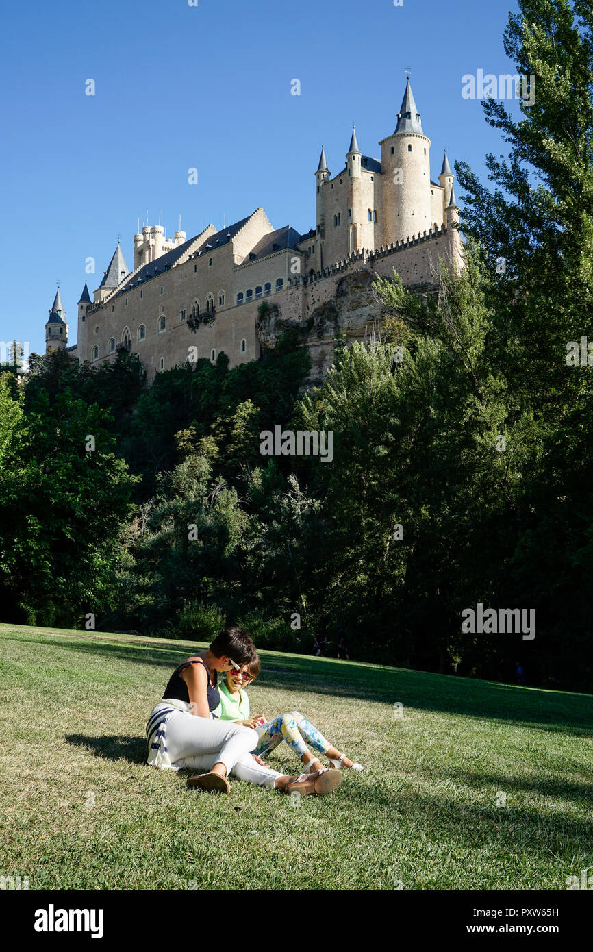 L'Espagne, Castille et Léon, Segovia, la mère et la fille assise sur l'herbe près de Alcazar de Ségovie Banque D'Images