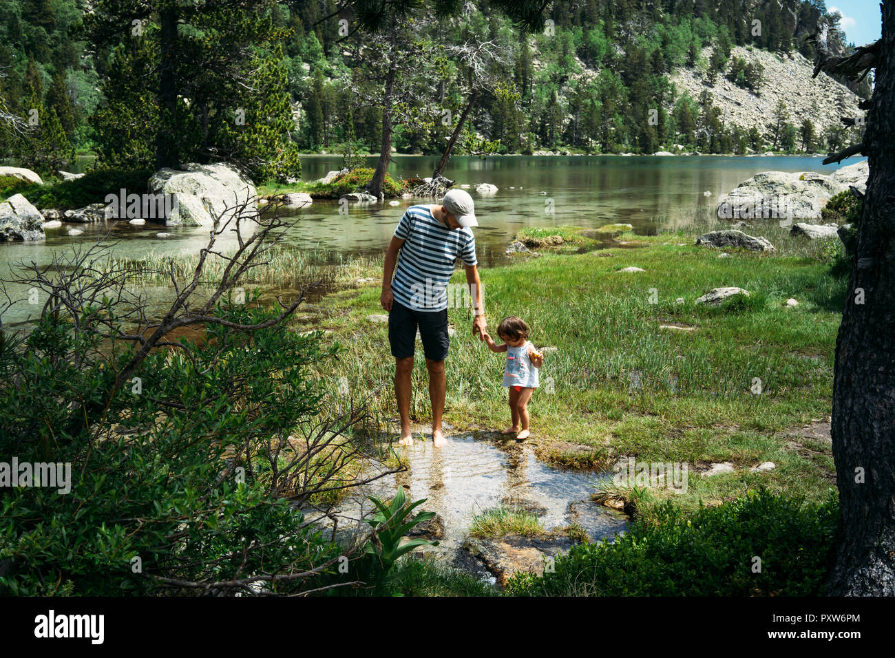 L'Espagne, père et fille explorer mountain lake, debout dans l'eau jusqu'aux chevilles Banque D'Images