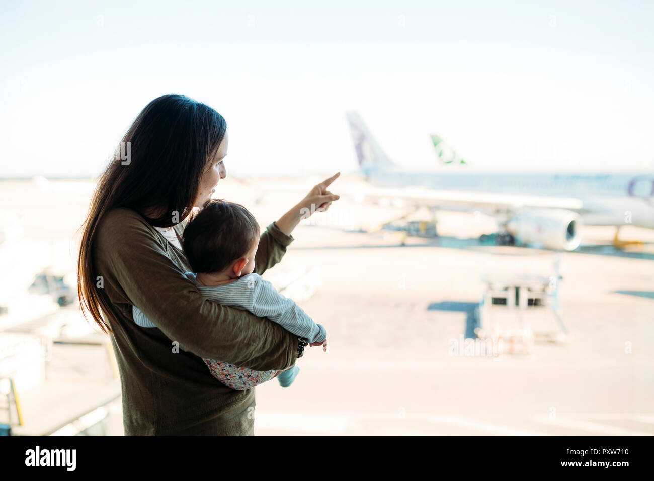 Mère tenant une petite fille à l'aéroport, pointant sur les avions Banque D'Images
