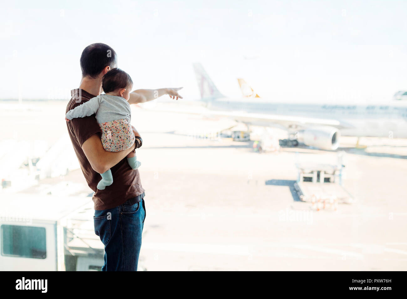 Espagne, Barcelone, Man holding a baby girl à l'aéroport en montrant les avions Banque D'Images