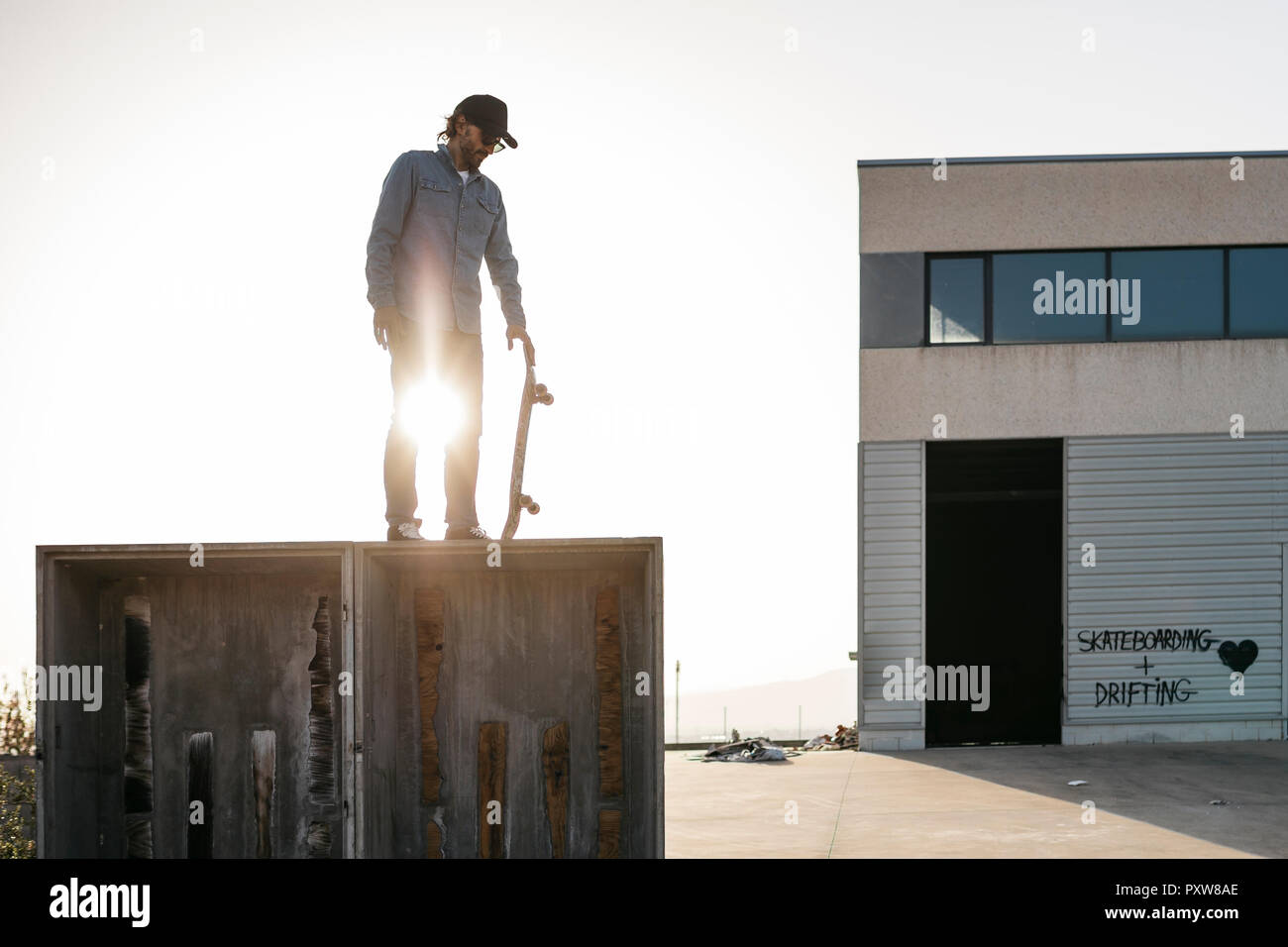 Vêtus de vêtements décontractés Skateboarder sur le dessus d'une boîte en bois, prêt à sauter Banque D'Images