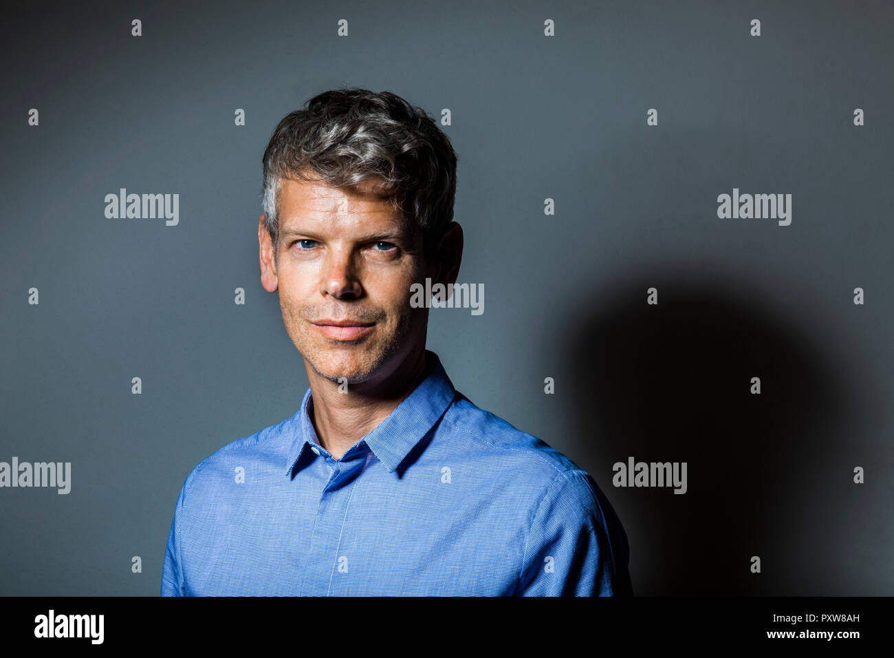 Portrait d'homme mûr avec des cheveux gris wearing blue shirt Banque D'Images