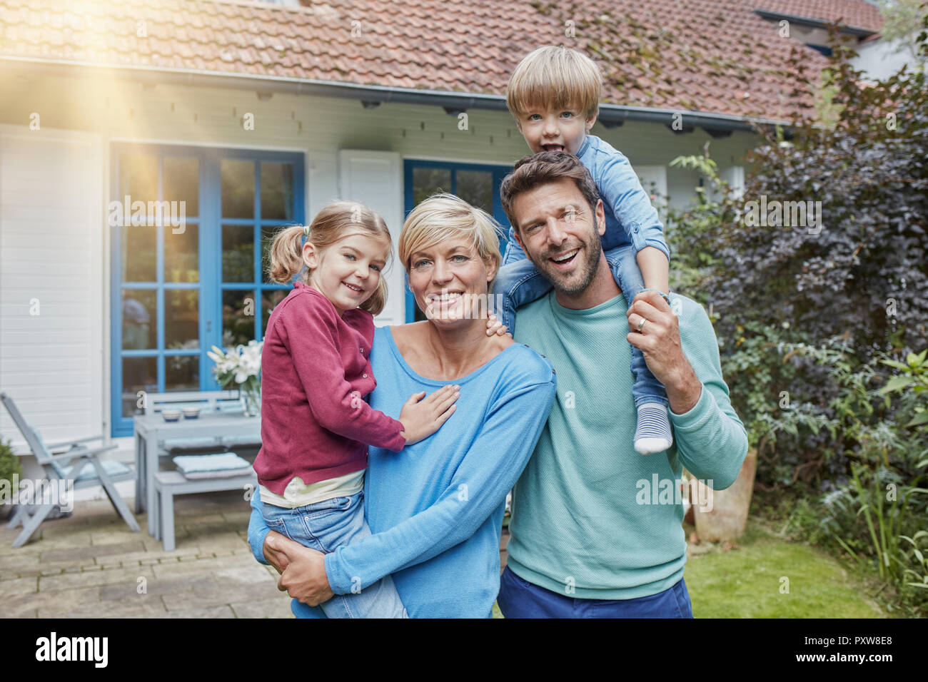 Portrait de famille heureuse avec deux enfants devant leur maison Banque D'Images