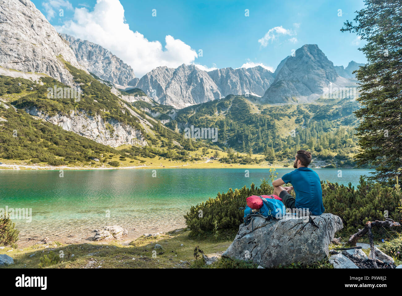 Autriche, Tyrol, randonneur prenant une pause, assis sur un rocher, à la recherche au lac Banque D'Images