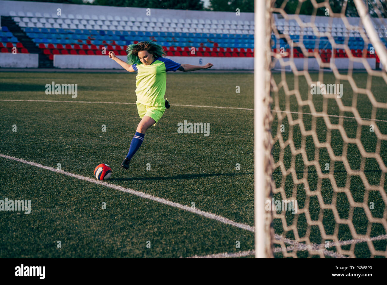 Jeune femme jouant au football sur terrain de football tir de la balle Banque D'Images