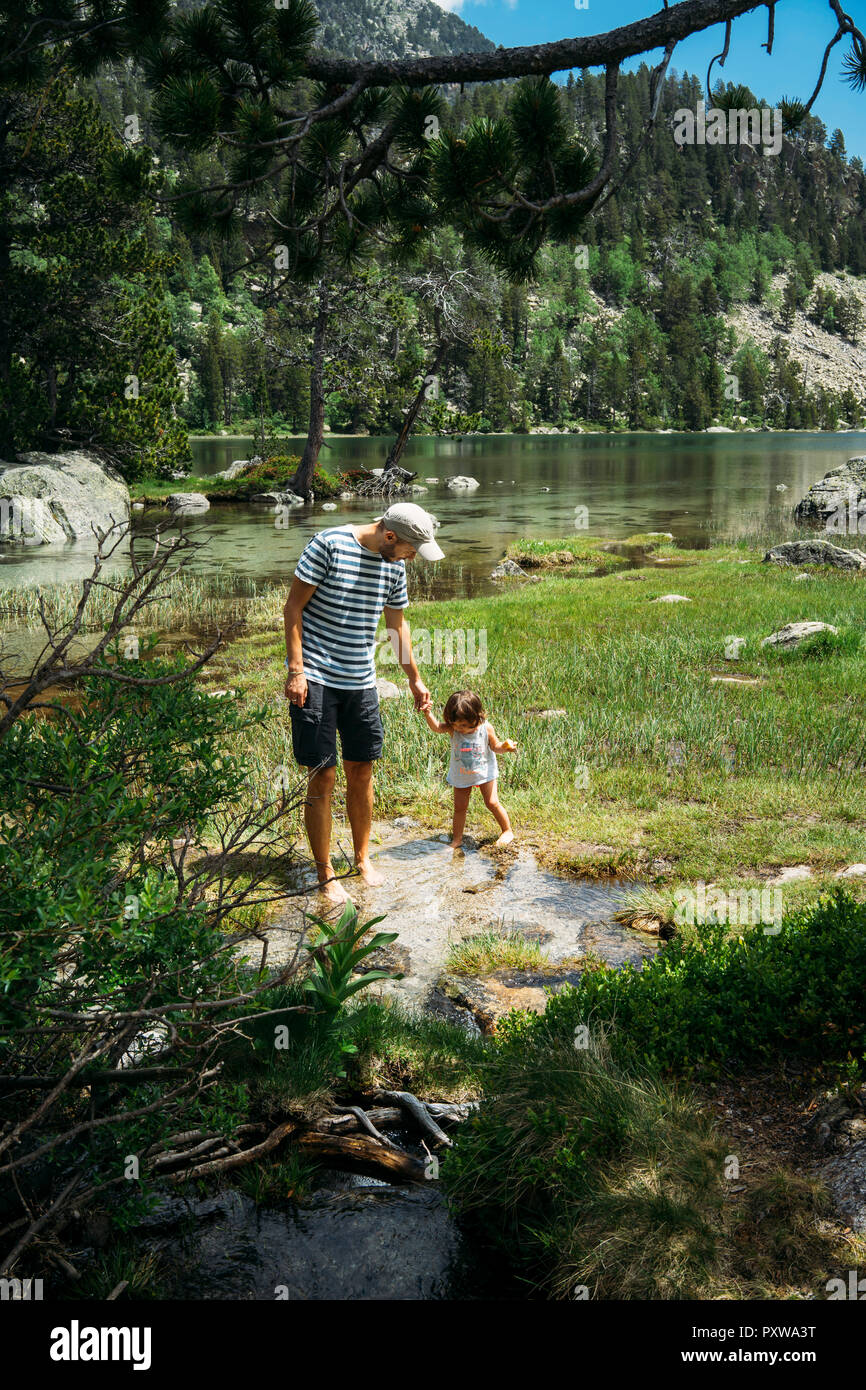 L'Espagne, père et fille explorer mountain lake, debout dans l'eau jusqu'aux chevilles Banque D'Images