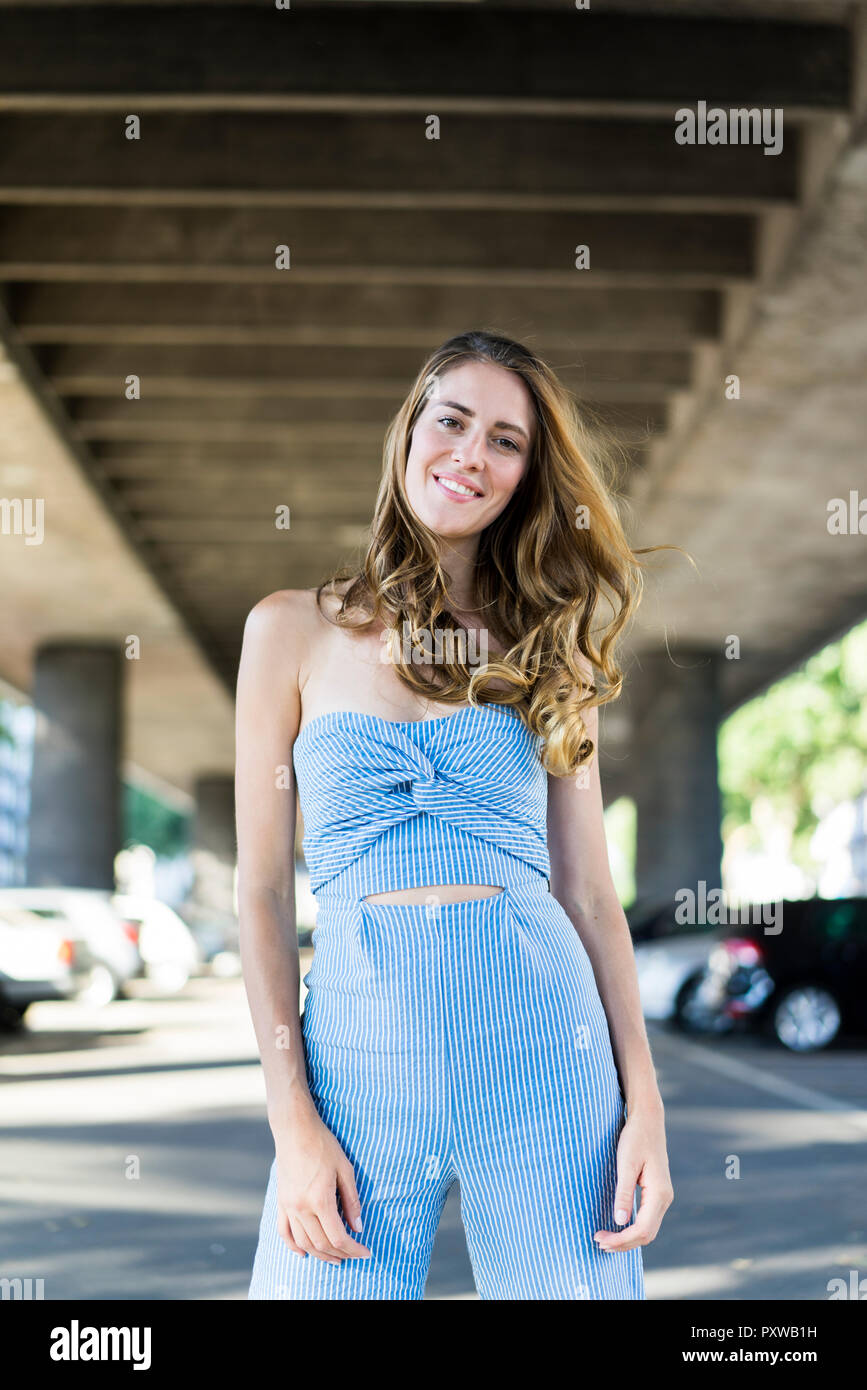 Portrait of smiling long-haired woman standing at passage sous Banque D'Images
