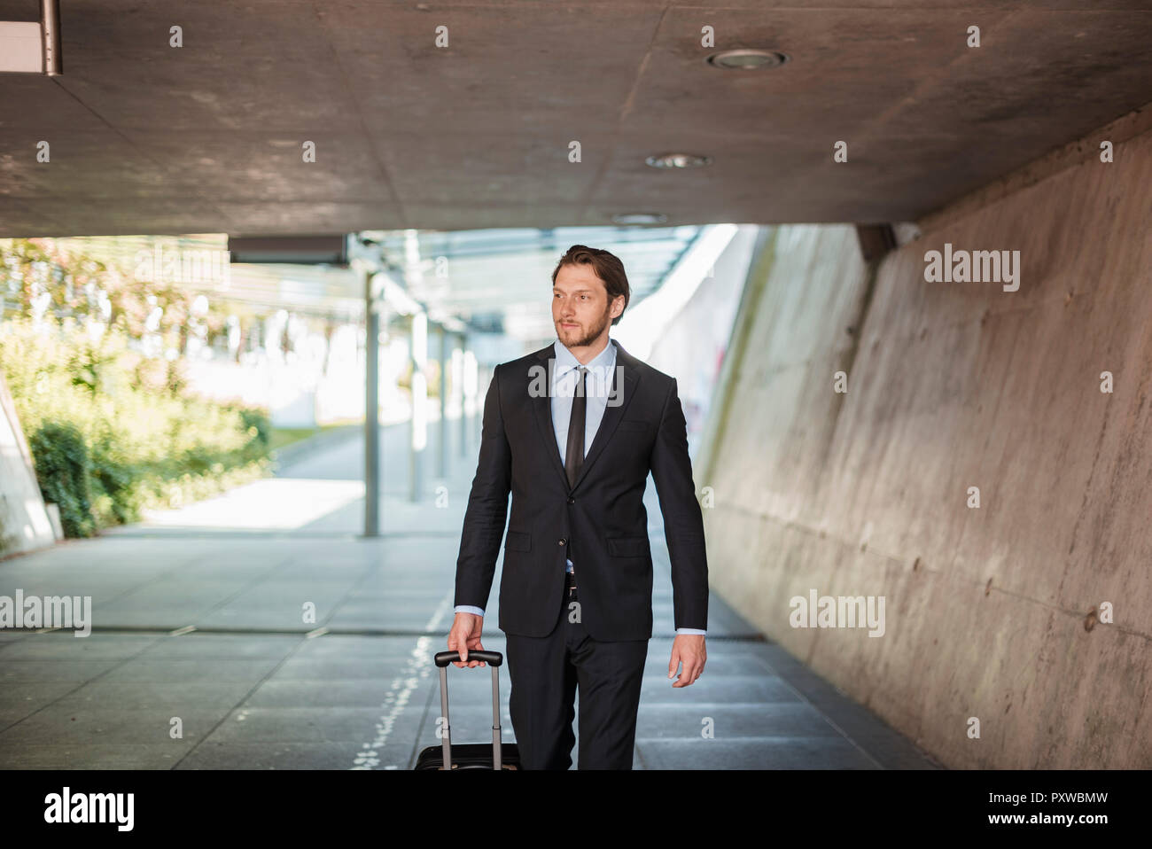 Businessman with rolling suitcase walking in tunnel Banque D'Images
