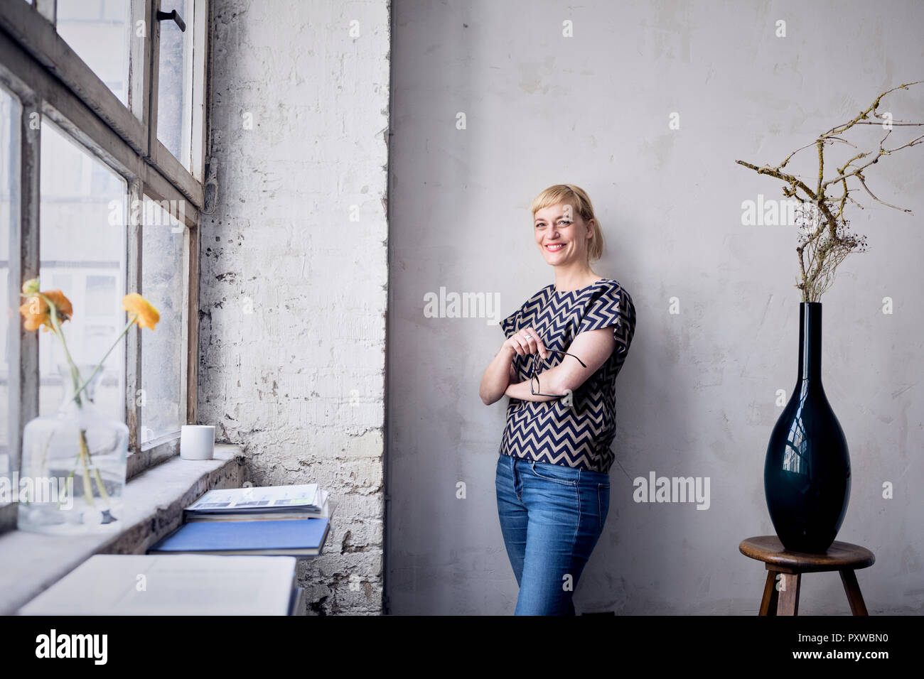 Portrait of laughing woman leaning against wall in loft Banque D'Images