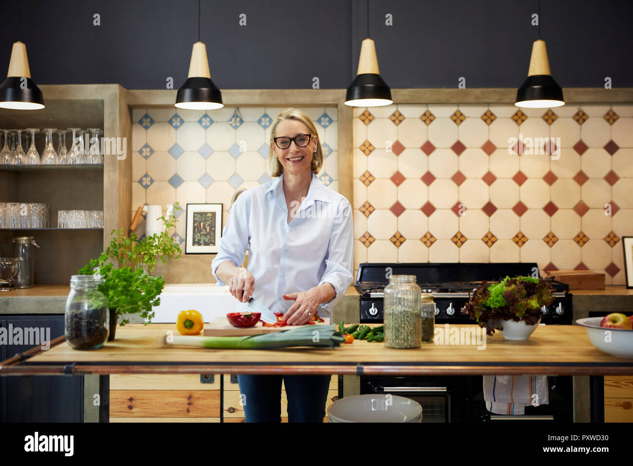 Portrait of smiling mature woman chopping poivron dans Cuisine Banque D'Images