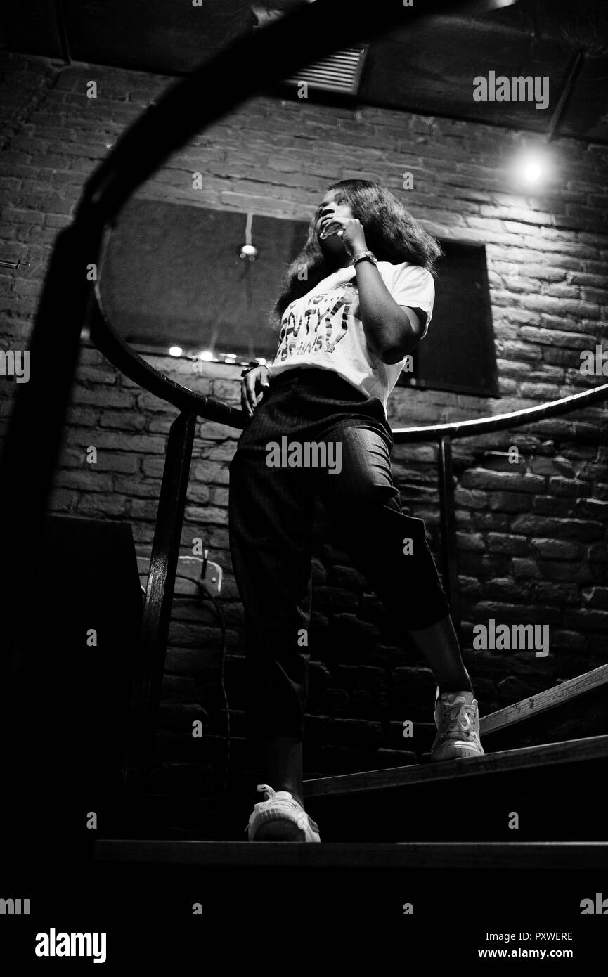 African American Woman in élégant T-shirt imprimé intérieur escaliers en acier posées. Banque D'Images